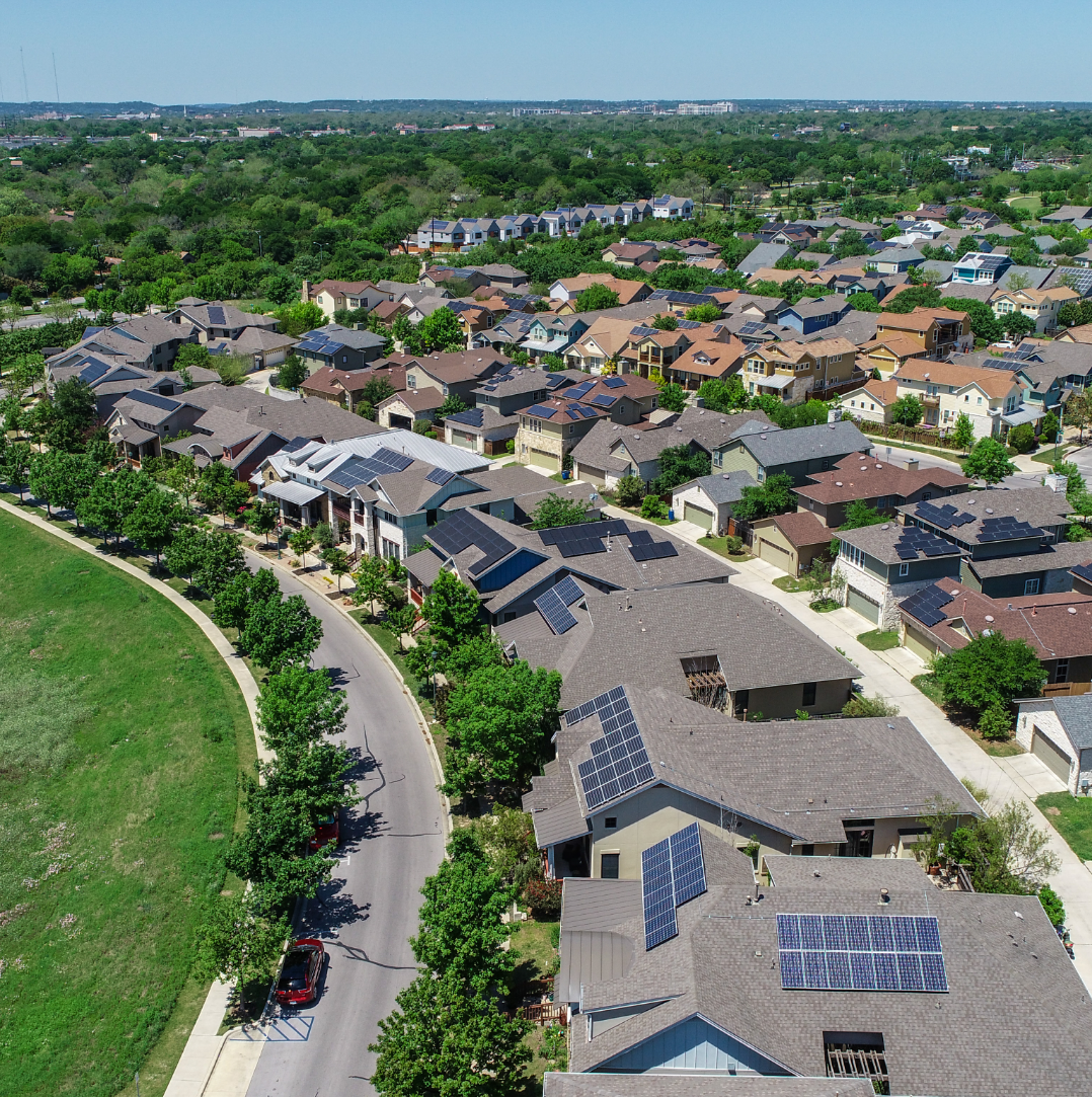 An overhead view of many homes in a neighborhood with solar panels.